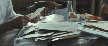 Movie still from “Oranges and Sunshine” (2010), directed by Jim Loach – A person holding a piece of paper on top of a pile of papers; Extreme Close Up shot, High angle