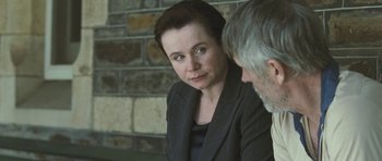 Movie still from “Oranges and Sunshine” (2010), directed by Jim Loach – A woman in a black jacket and a man in a gray suit; Close Up shot, Over the shoulder angle
