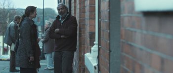Movie still from “Oranges and Sunshine” (2010), directed by Jim Loach – A man standing in front of a brick building; Medium shot, Over the shoulder angle