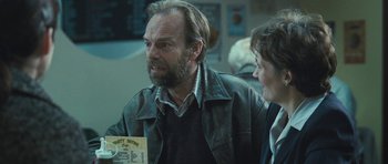 Movie still from “Oranges and Sunshine” (2010), directed by Jim Loach – A man and a woman sitting next to each other in a room; Medium shot, Over the shoulder angle
