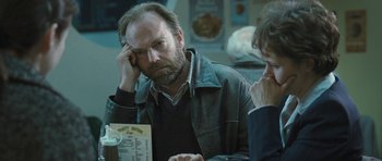 Movie still from “Oranges and Sunshine” (2010), directed by Jim Loach – A man sitting in front of a table with another man; Close Up shot, Over the shoulder angle