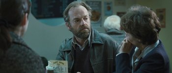 Movie still from “Oranges and Sunshine” (2010), directed by Jim Loach – A man in a leather jacket sitting at a table; Close Up shot, Over the shoulder angle