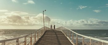 Movie still from “Oranges and Sunshine” (2010), directed by Jim Loach – Two people are standing on a pier looking out at the ocean; Extreme Wide shot, High angle