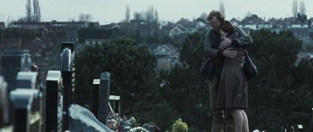 Movie still from “Oranges and Sunshine” (2010), directed by Jim Loach – Two people standing in front of a grave in a cemetery; Medium shot, Low angle