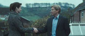 Movie still from “Oranges and Sunshine” (2010), directed by Jim Loach – A man in a suit shaking hands with another man in a blue shirt; Medium shot, Over the shoulder angle