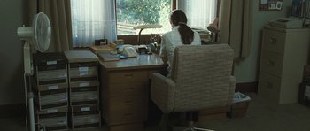 Movie still from “Oranges and Sunshine” (2010), directed by Jim Loach – A woman sitting at a desk in front of a window; Wide shot, High angle