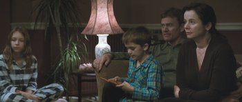 Movie still from “Oranges and Sunshine” (2010), directed by Jim Loach – A man and a boy sitting in a living room next to each other; Medium shot, Over the shoulder angle