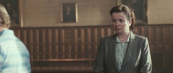 Movie still from “Oranges and Sunshine” (2010), directed by Jim Loach – A woman in a suit standing in front of a wooden bench; Medium shot, Low angle