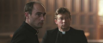 Movie still from “Oranges and Sunshine” (2010), directed by Jim Loach – A priest and a man in a black outfit; Close Up shot, Over the shoulder angle