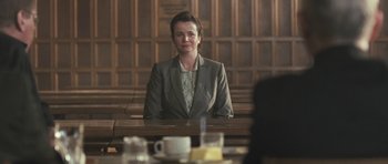 Movie still from “Oranges and Sunshine” (2010), directed by Jim Loach – A woman sitting at a table in a courtroom; Medium shot, Over the shoulder angle