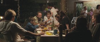 Movie still from “Oranges and Sunshine” (2010), directed by Jim Loach – A group of people sitting at a table with food on it; Wide shot, Over the shoulder angle