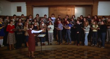Movie still from “Ordinary People” (1980), directed by Robert Redford – A group of people standing in a room with musical instruments; Wide shot, High angle