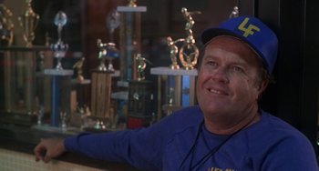 Movie still from “Ordinary People” (1980), directed by Robert Redford – A man sitting in front of many trophies in a room; Close Up shot, Over the shoulder angle