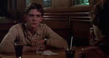 Movie still from “Ordinary People” (1980), directed by Robert Redford – A man sitting at a table with a drink in front of him; Close Up shot, Over the shoulder angle