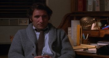 Movie still from “Ordinary People” (1980), directed by Robert Redford – A man sitting at a desk wearing a sweater and a tie; Close Up shot, High angle