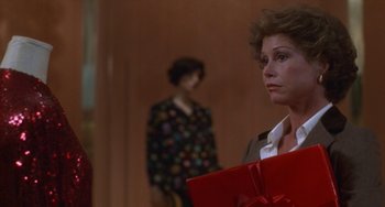 Movie still from “Ordinary People” (1980), directed by Robert Redford – A woman holding a red gift bag in front of a woman; Close Up shot, Over the shoulder angle