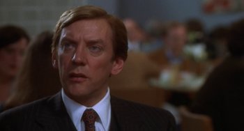 Movie still from “Ordinary People” (1980), directed by Robert Redford – A man in a suit and tie in front of a group of people; Close Up shot, Over the shoulder angle