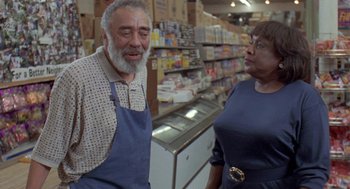 Movie still from “Original Gangstas” (1996), directed by Larry Cohen – An older man and a woman in a grocery store; Medium shot, Low angle