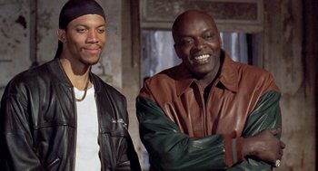 Movie still from “Original Gangstas” (1996), directed by Larry Cohen – A couple of men standing next to each other; Medium shot, Low angle