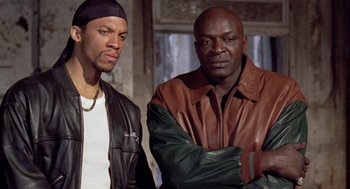Movie still from “Original Gangstas” (1996), directed by Larry Cohen – A couple of men standing next to each other; Medium shot, Low angle