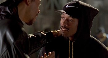 Movie still from “Original Gangstas” (1996), directed by Larry Cohen – A man in a black jacket and a man in a black hat; Close Up shot, Over the shoulder angle