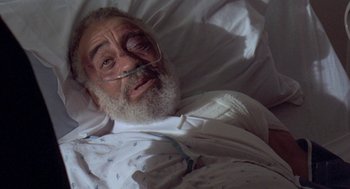 Movie still from “Original Gangstas” (1996), directed by Larry Cohen – An old man with a beard and a mustache is laying in a hospital bed; Close Up shot, Overhead angle