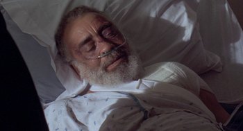 Movie still from “Original Gangstas” (1996), directed by Larry Cohen – An old man with a beard and a mustache is laying in a hospital bed; Close Up shot, High angle