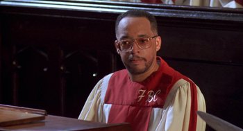 Movie still from “Original Gangstas” (1996), directed by Larry Cohen – A man wearing glasses and a red and white robe; Close Up shot, Low angle