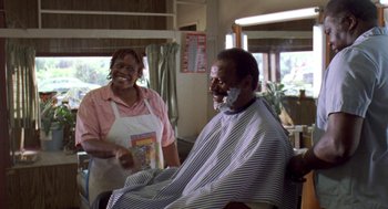 Movie still from “Original Gangstas” (1996), directed by Larry Cohen – A man getting his hair cut at a barber shop; Medium shot, Over the shoulder angle