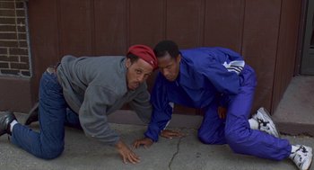 Movie still from “Original Gangstas” (1996), directed by Larry Cohen – A couple of men are laying on the ground together; Medium shot, Low angle