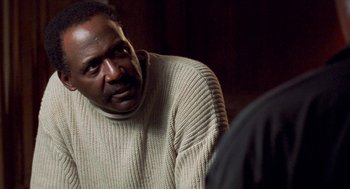 Movie still from “Original Gangstas” (1996), directed by Larry Cohen – A man wearing a sweater is looking at the camera; Close Up shot, Over the shoulder angle