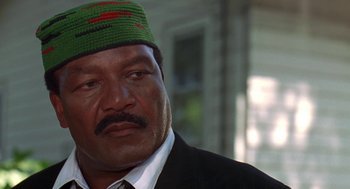 Movie still from “Original Gangstas” (1996), directed by Larry Cohen – A person wearing a suit and a hat; Close Up shot, Low angle