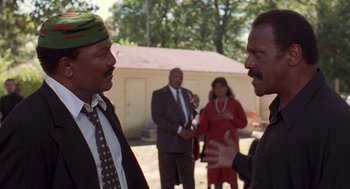 Movie still from “Original Gangstas” (1996), directed by Larry Cohen – Two men talking to each other in front of a group of people; Medium shot, Low angle
