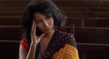 Movie still from “Original Gangstas” (1996), directed by Larry Cohen – A woman in a black and orange dress is looking at the camera; Close Up shot, High angle