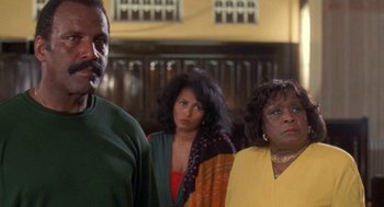 Movie still from “Original Gangstas” (1996), directed by Larry Cohen – A group of people standing next to each other in a room; Medium shot, Low angle