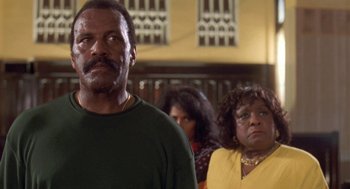 Movie still from “Original Gangstas” (1996), directed by Larry Cohen – A man and a woman standing next to each other in a room; Close Up shot, Low angle