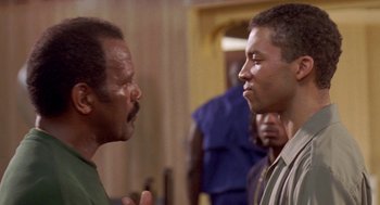 Movie still from “Original Gangstas” (1996), directed by Larry Cohen – Two men talking to each other in front of a group of people; Close Up shot, Over the shoulder angle