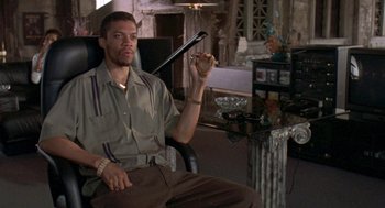 Movie still from “Original Gangstas” (1996), directed by Larry Cohen – A man sitting in a chair holding a baseball bat; Medium shot, High angle
