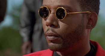 Movie still from “Original Gangstas” (1996), directed by Larry Cohen – A person wearing round sunglasses; Close Up shot, Low angle