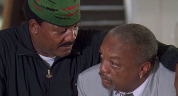 Movie still from “Original Gangstas” (1996), directed by Larry Cohen – A man in a green hat is hugging another man; Close Up shot, High angle