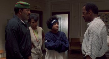 Movie still from “Original Gangstas” (1996), directed by Larry Cohen – A group of people standing in a living room; Medium shot, Over the shoulder angle