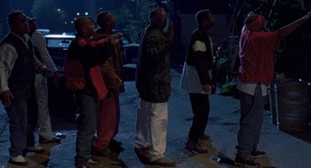 Movie still from “Original Gangstas” (1996), directed by Larry Cohen – A group of people standing on a street at night; Wide shot, Low angle