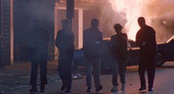 Movie still from “Original Gangstas” (1996), directed by Larry Cohen – A group of people walking down a street near a fire; Wide shot, Low angle