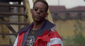 Movie still from “Original Gangstas” (1996), directed by Larry Cohen – A person wearing sunglasses and a jacket; Close Up shot, Low angle