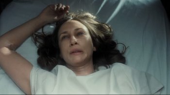 Movie still from “Orphan” (2009), directed by Jaume Collet-Serra – A woman laying in a bed with her head on the ground; Close Up shot, Overhead angle