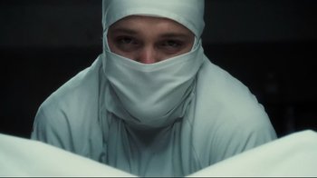 Movie still from “Orphan” (2009), directed by Jaume Collet-Serra – A man wearing a white surgical gown and a white head covering; Close Up shot, Low angle
