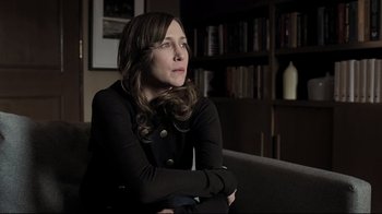 Movie still from “Orphan” (2009), directed by Jaume Collet-Serra – A woman sitting on top of a couch in a living room; Medium shot, Over the shoulder angle