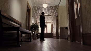 Movie still from “Orphan” (2009), directed by Jaume Collet-Serra – A man standing in a hallway of a building; Wide shot, Low angle