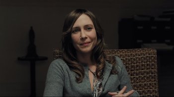 Movie still from “Orphan” (2009), directed by Jaume Collet-Serra – A woman sitting in a chair smiling for the camera; Close Up shot, Over the shoulder angle