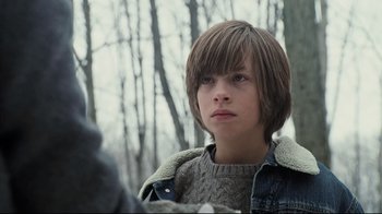 Movie still from “Orphan” (2009), directed by Jaume Collet-Serra – A young boy with brown hair wearing a sweater and a jacket; Close Up shot, Low angle